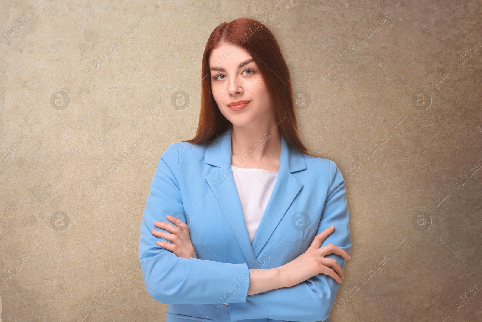 Image of Portrait of beautiful business woman with crossed arms on beige textured background