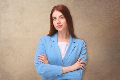 Portrait of beautiful business woman with crossed arms on beige textured background