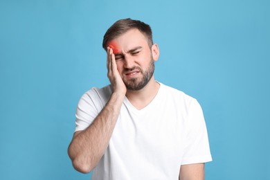 Image of Man suffering from headache on light blue background