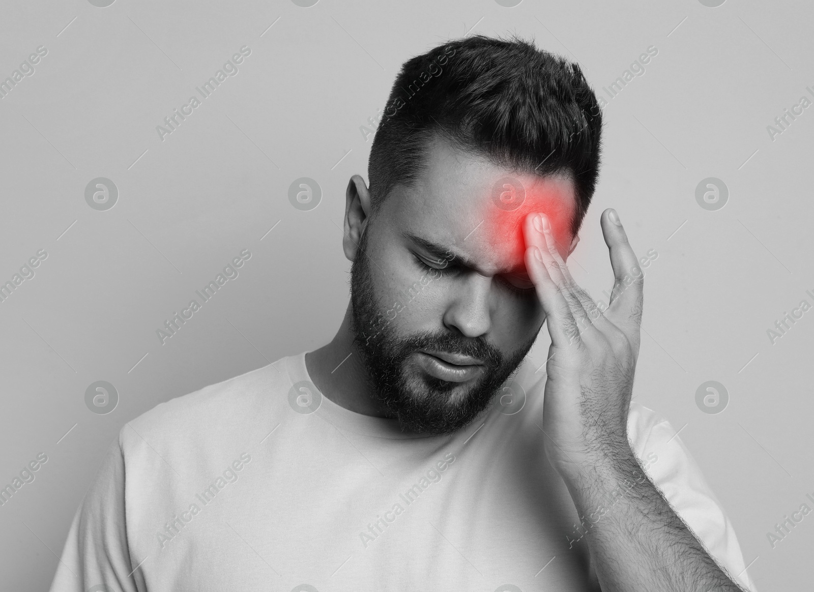 Image of Man suffering from headache on light background. Black and white effect with red color accent