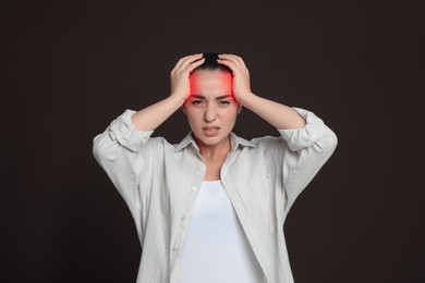 Image of Young woman suffering from headache on dark brown background