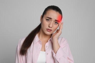 Image of Young woman suffering from headache on grey background