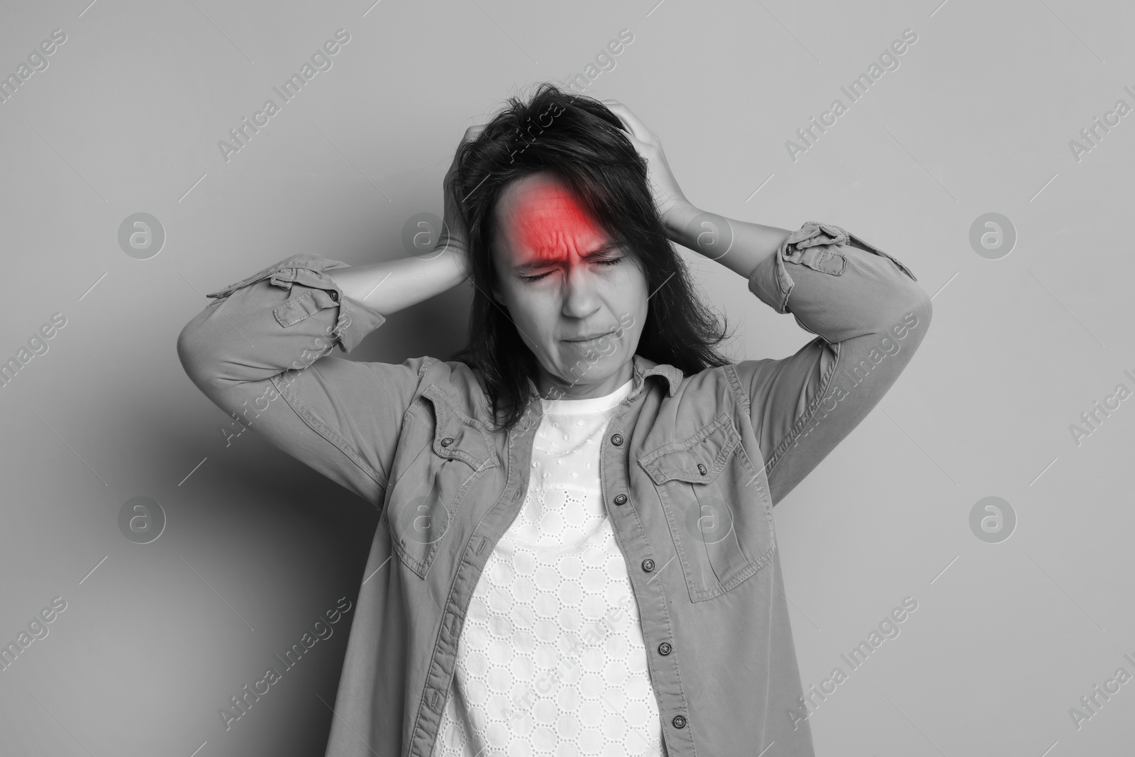 Image of Woman suffering from headache on light background. Black and white effect with red color accent