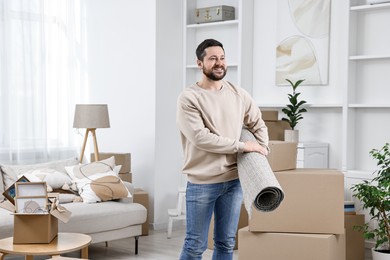 Moving day. Happy man with rug in his new home