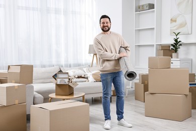 Photo of Moving day. Happy man with rug in his new home