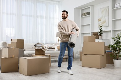 Photo of Moving day. Happy man with rug in his new home