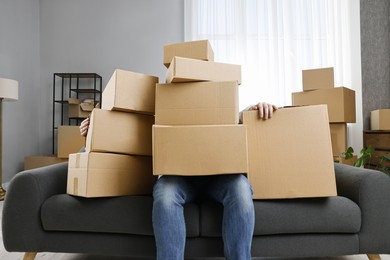 Photo of Moving day. Man with cardboard boxes on sofa in his new home