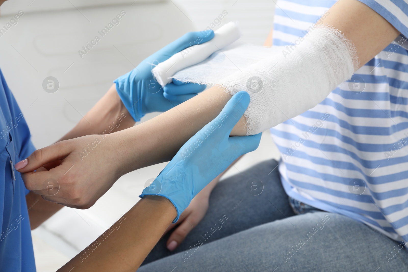 Photo of Doctor bandaging patient's elbow in clinic, closeup