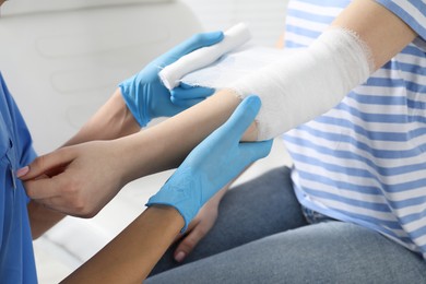 Photo of Doctor bandaging patient's elbow in clinic, closeup