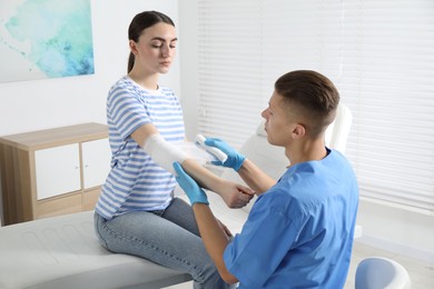 Photo of Doctor applying bandage onto patient's elbow in clinic