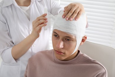 Photo of Doctor bandaging patient's head in clinic, closeup