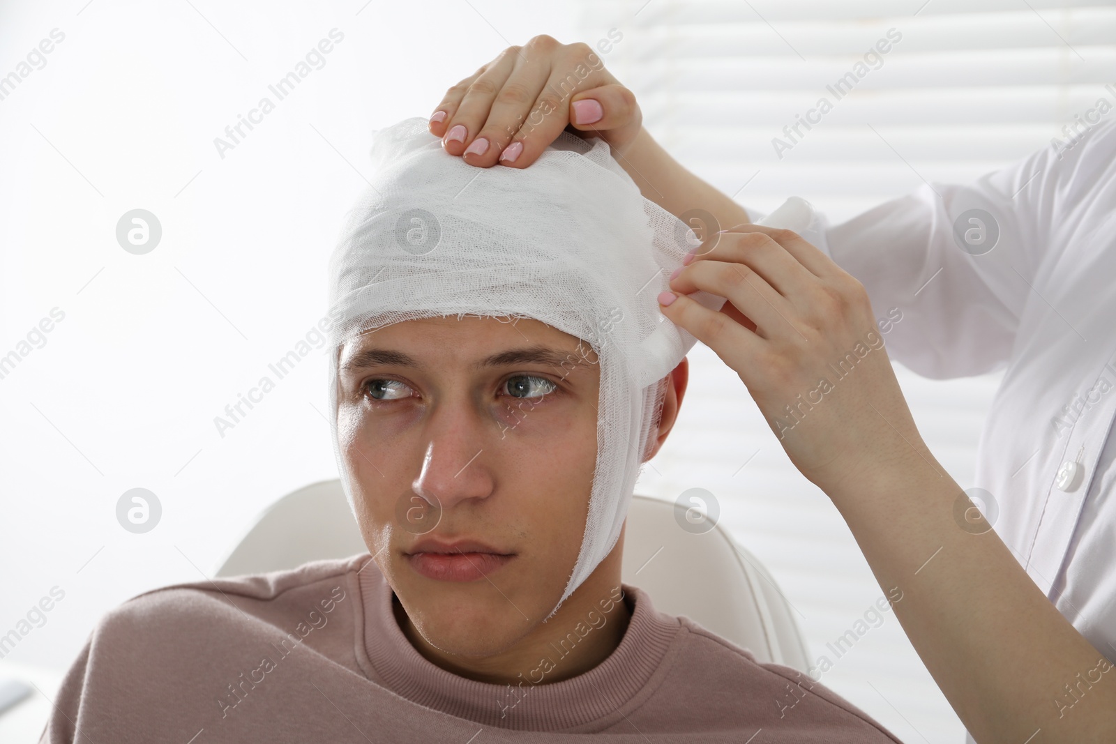 Photo of Doctor bandaging patient's head in clinic, closeup