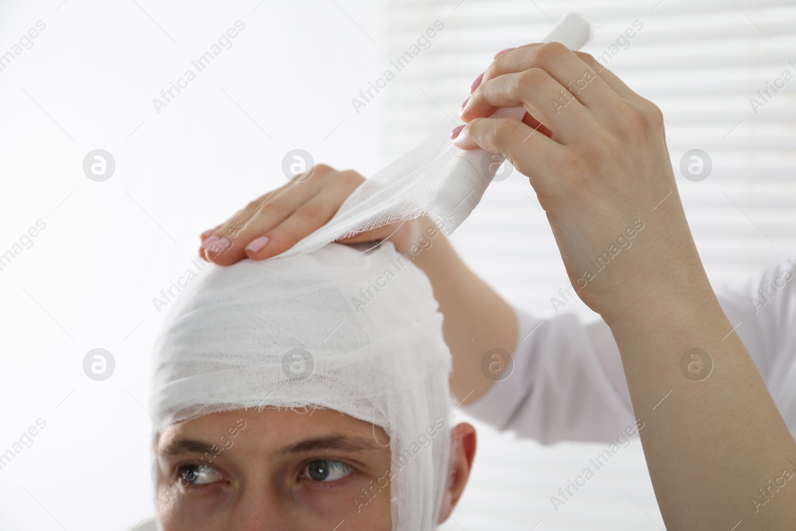 Photo of Doctor bandaging patient's head in clinic, closeup