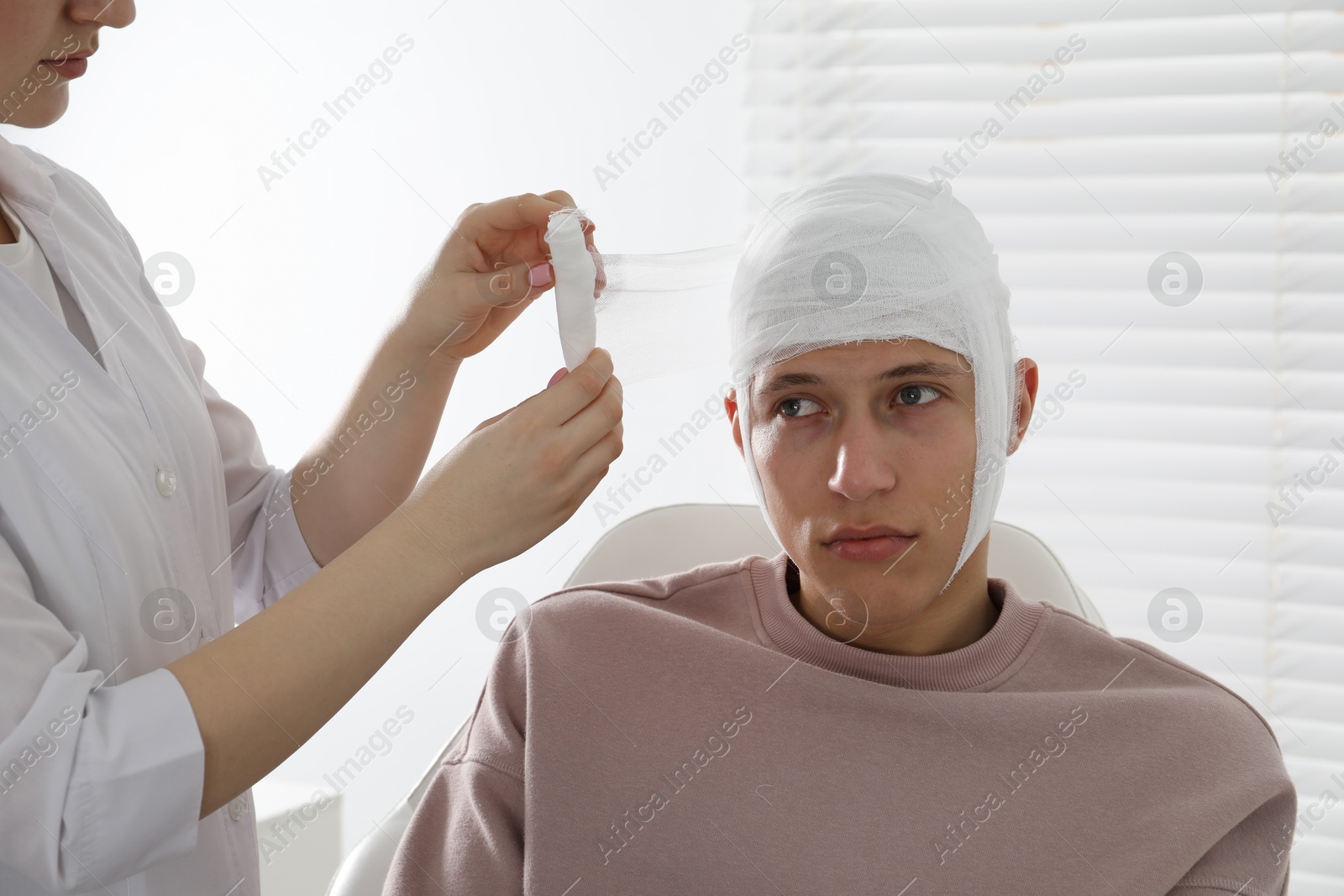 Doctor bandaging patient's head in clinic, closeup Photo of Doctor bandaging patient's head in clinic, closeup