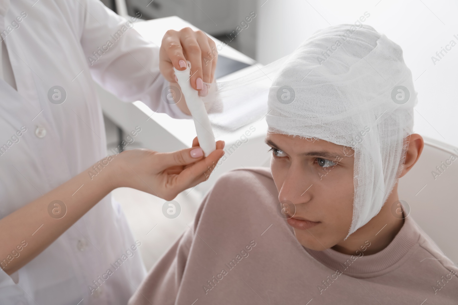 Photo of Doctor bandaging patient's head in clinic, closeup