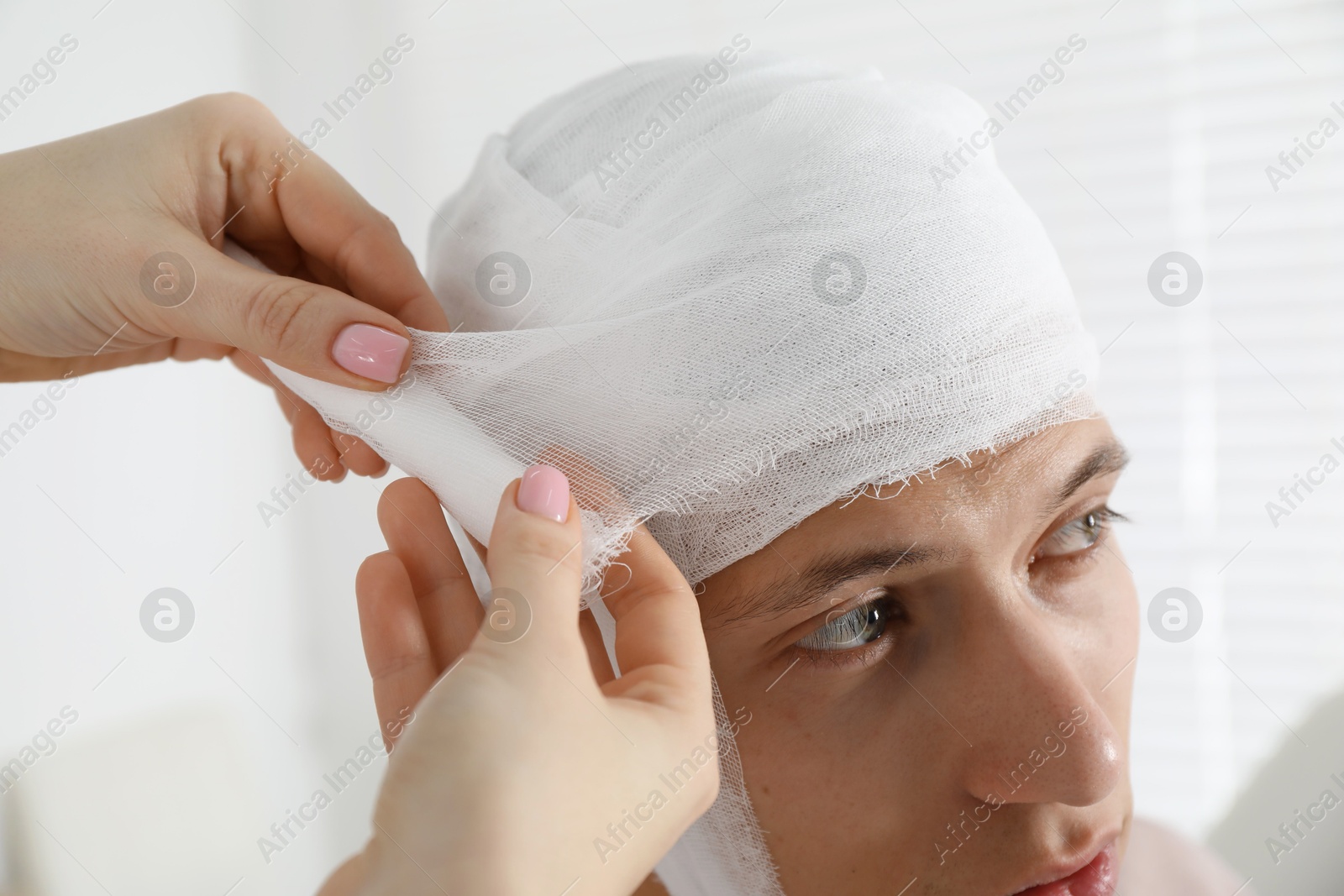 Photo of Doctor bandaging patient's head in clinic, closeup