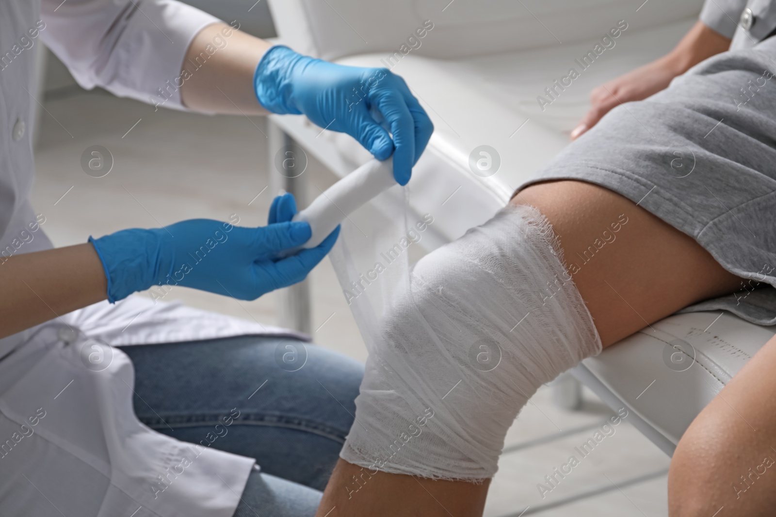 Photo of Doctor bandaging patient's knee in clinic, closeup