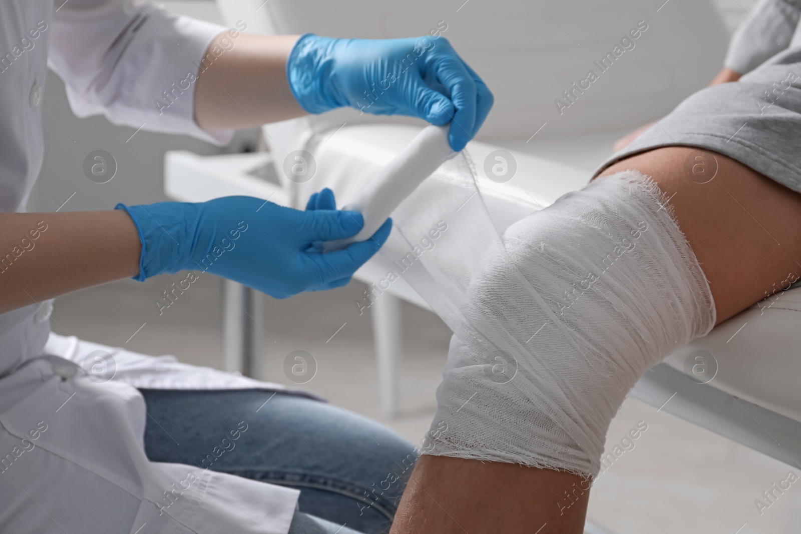 Photo of Doctor bandaging patient's knee in clinic, closeup