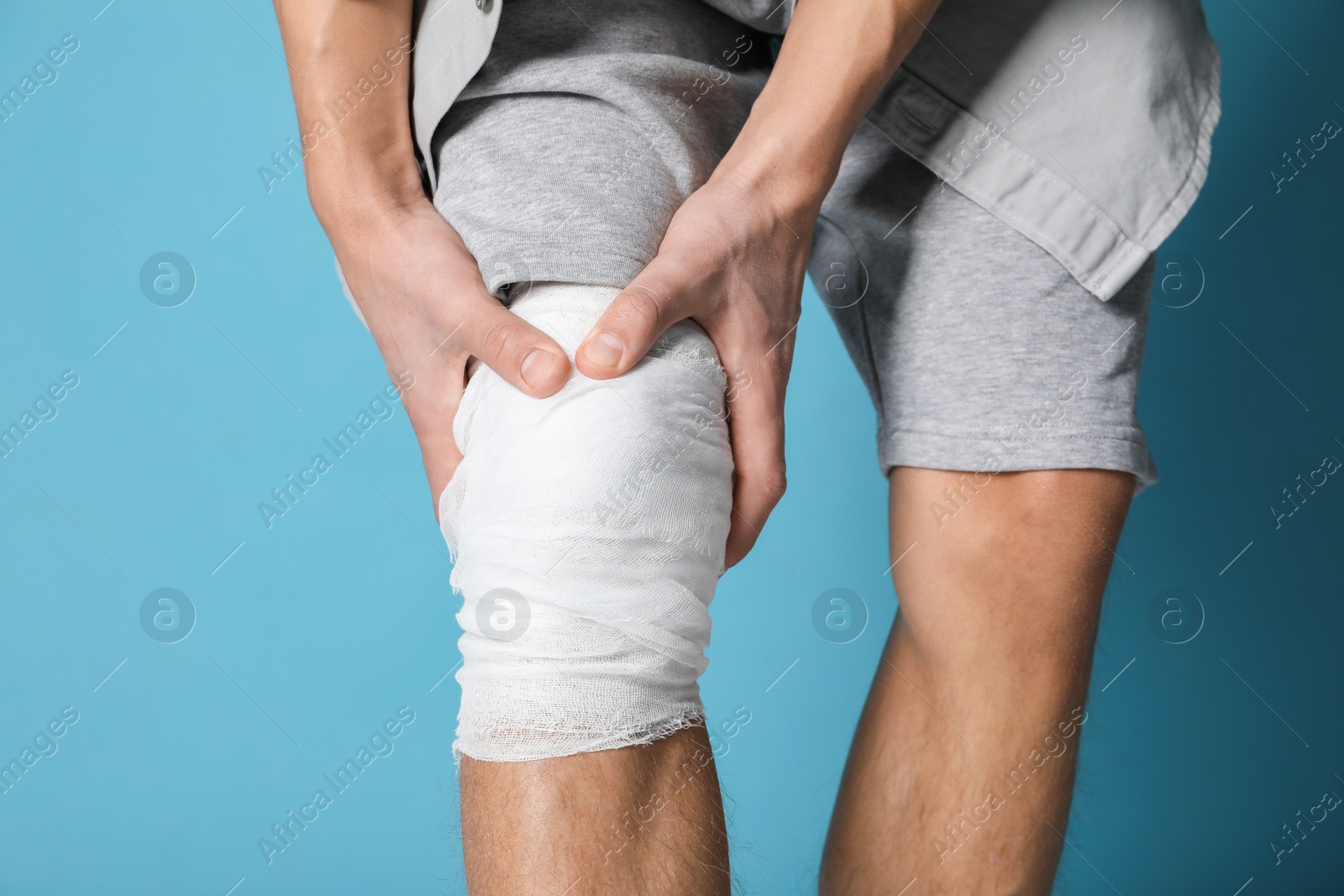 Photo of Man with medical bandage on his knee against light blue background, closeup