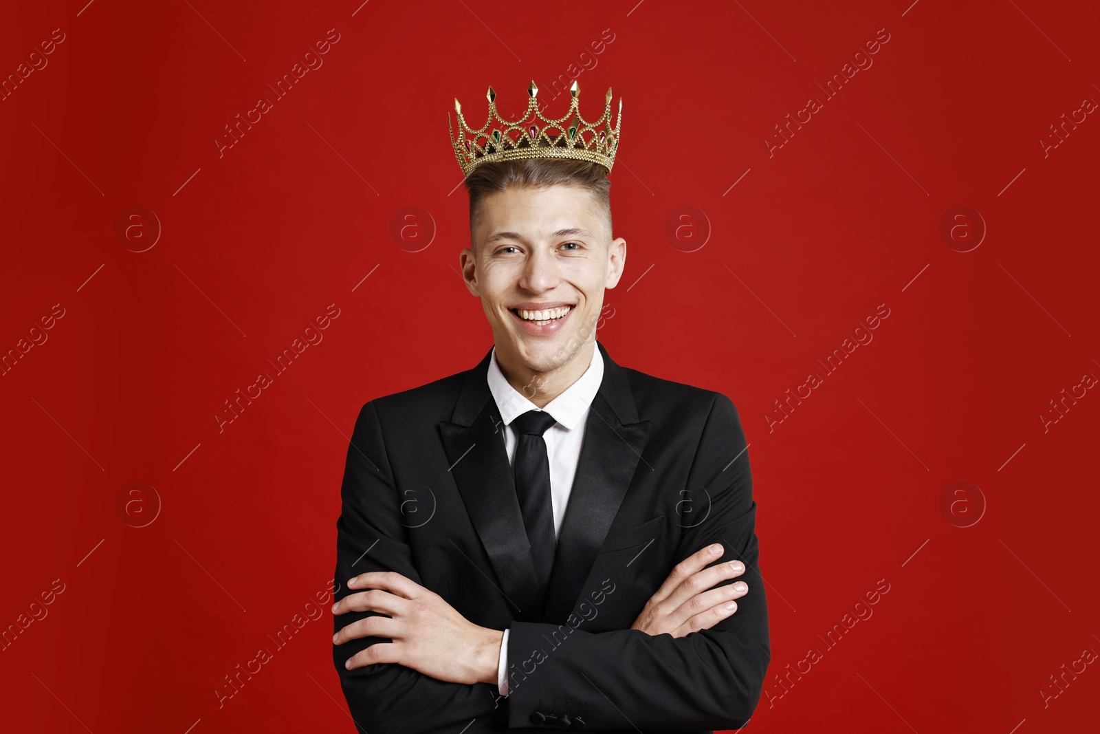 Photo of Handsome man wearing luxury crown on red background