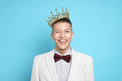 Handsome man wearing luxury crown on light blue background