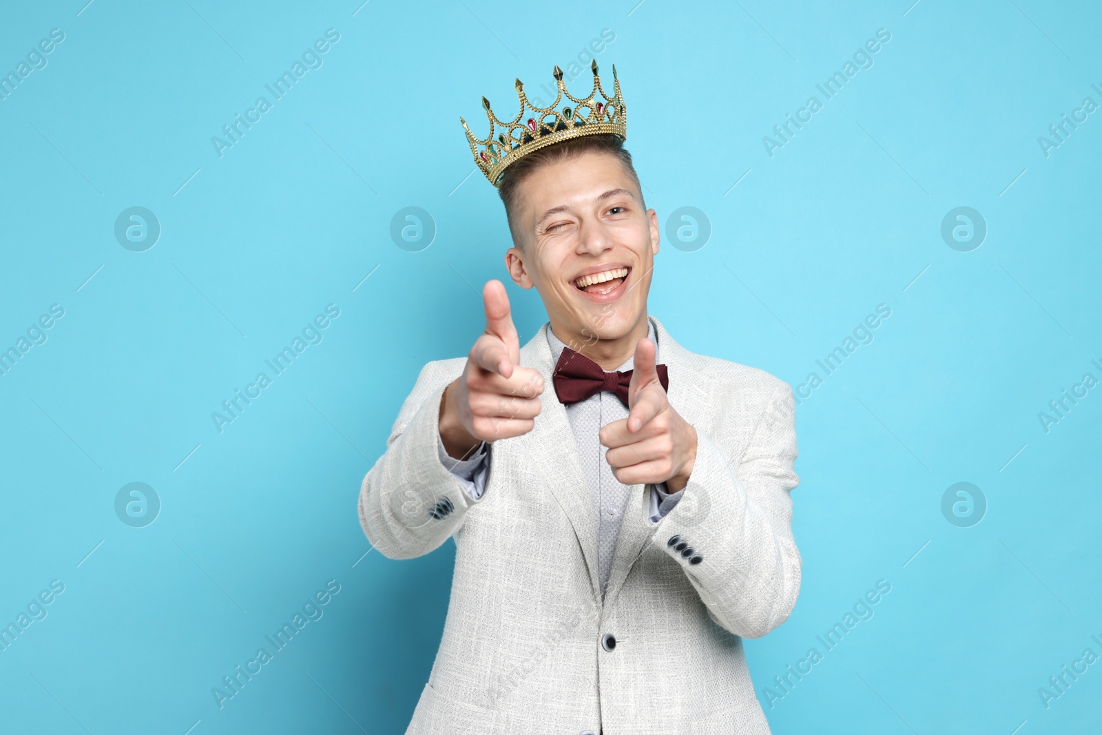 Photo of Handsome man wearing luxury crown on light blue background