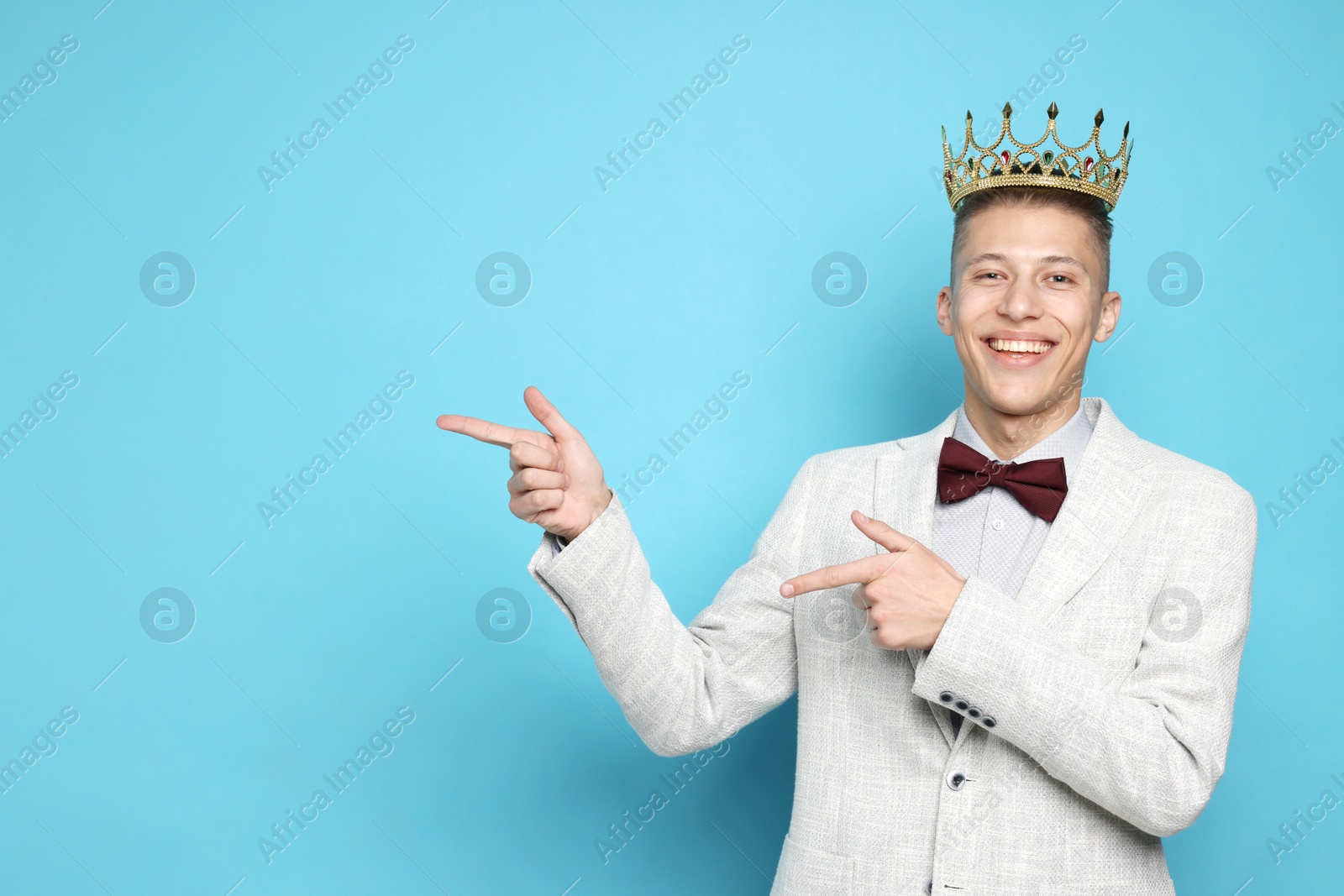 Photo of Handsome man wearing luxury crown on light blue background, space for text