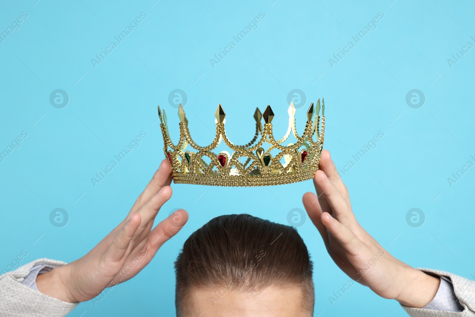 Photo of Man wearing luxury crown on light blue background, closeup