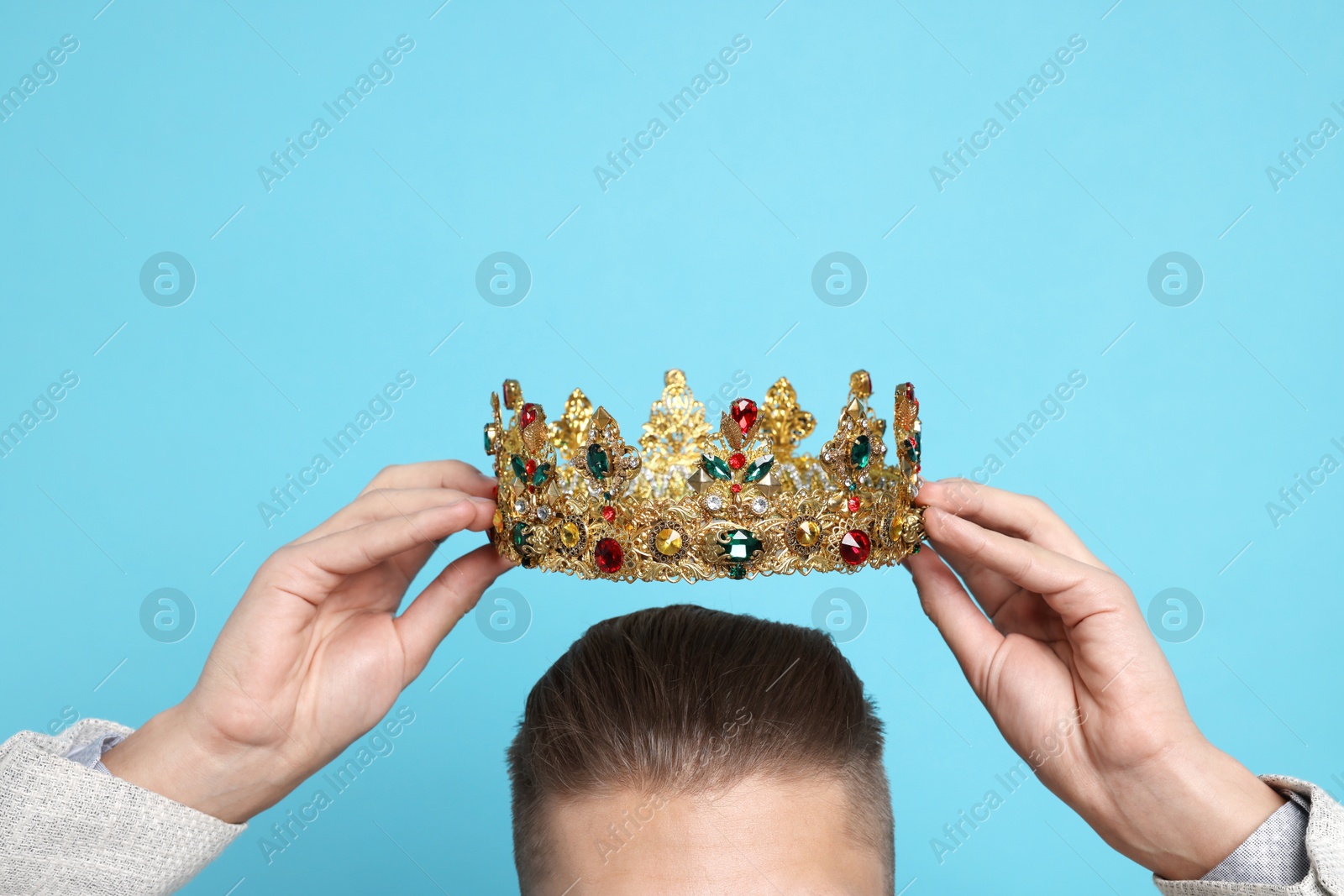 Photo of Man wearing luxury crown on light blue background, closeup