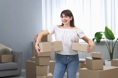 Photo of Moving day. Happy woman with cardboard boxes in her new home