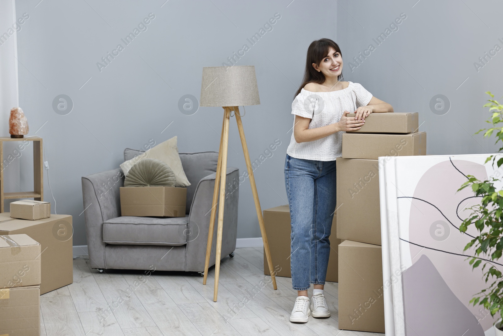 Photo of Moving day. Happy woman with her belongings in new home