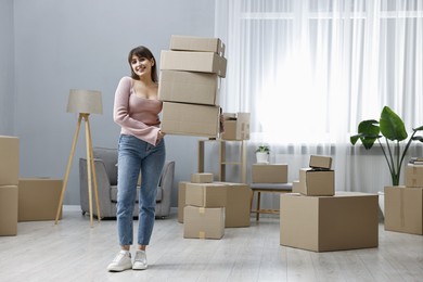 Photo of Moving day. Happy woman with cardboard boxes in her new home