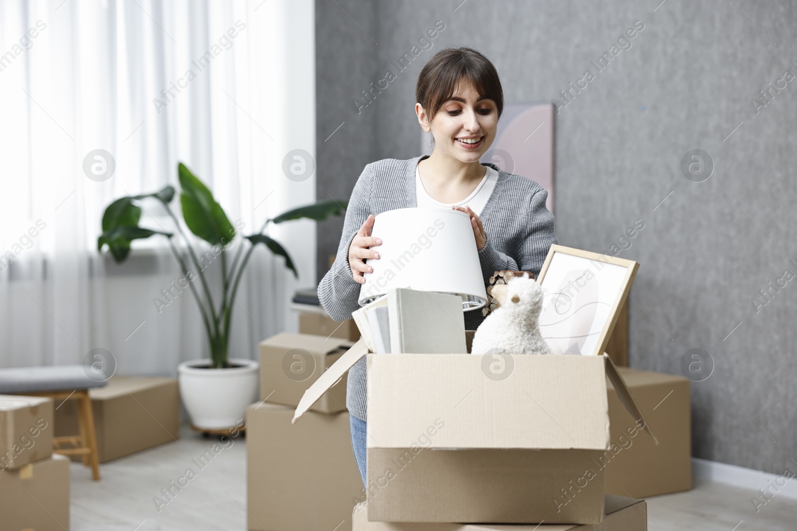 Photo of Moving day. Happy woman with her belongings in new home