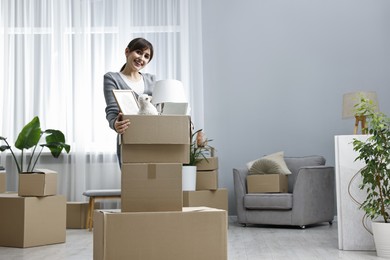 Photo of Moving day. Happy woman with her belongings in new home, space for text