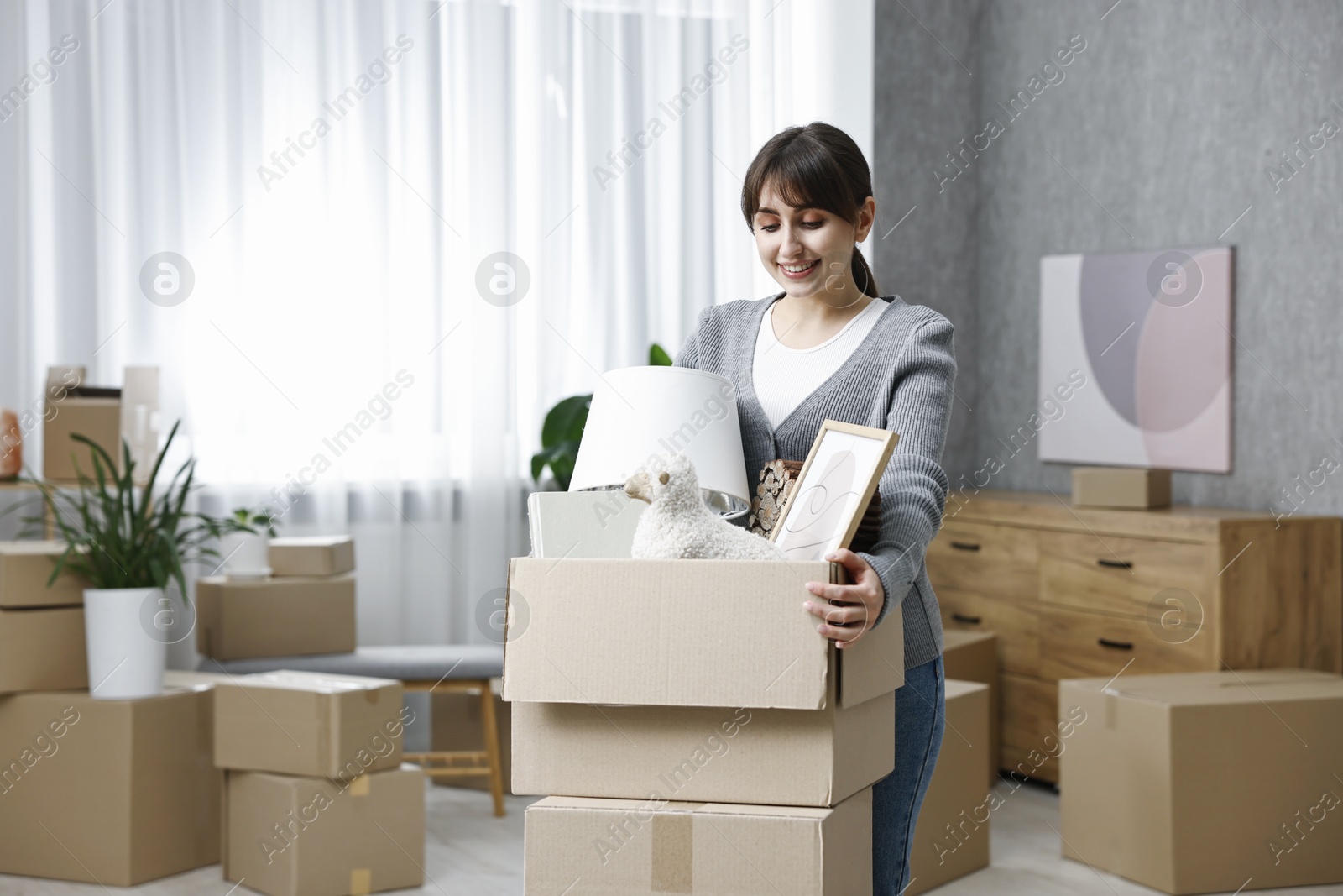 Photo of Moving day. Happy woman with her belongings in new home