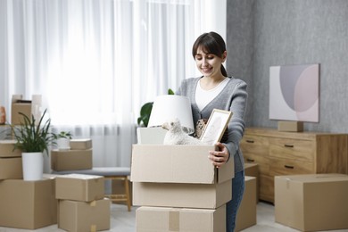 Photo of Moving day. Happy woman with her belongings in new home