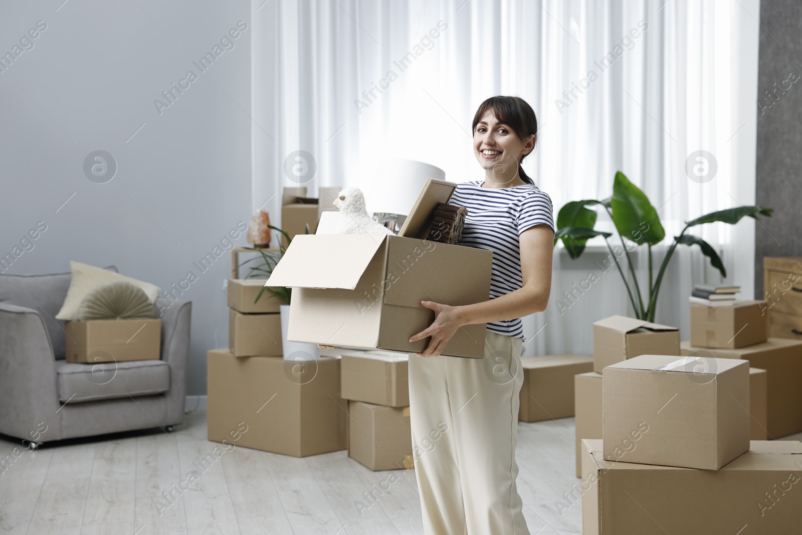 Photo of Moving day. Happy woman with her belongings in new home