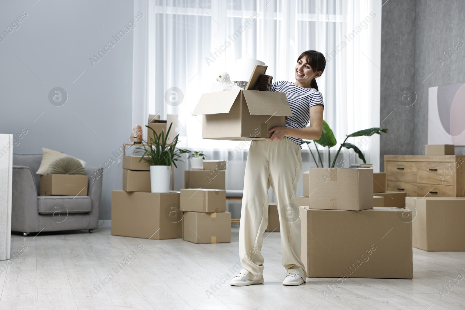 Photo of Moving day. Happy woman with her belongings in new home