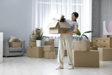 Photo of Moving day. Happy woman with her belongings in new home