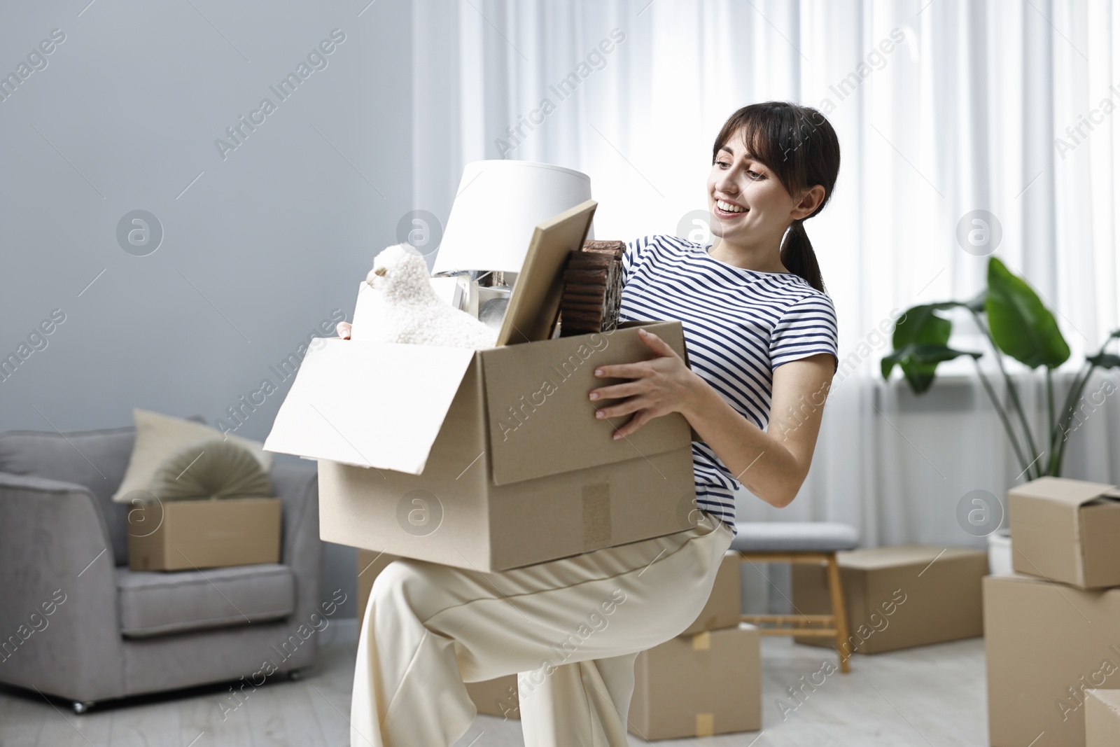 Photo of Moving day. Happy woman with her belongings in new home