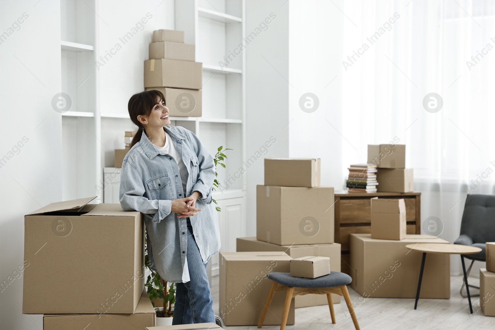 Photo of Moving day. Happy woman with her belongings in new home