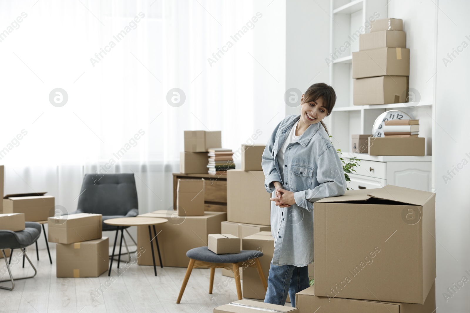 Photo of Moving day. Happy woman with her belongings in new home