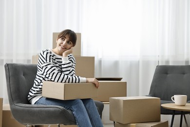 Photo of Moving day. Happy woman with cardboard box in her new home