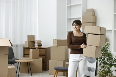 Photo of Moving day. Happy woman with cardboard boxes in her new home