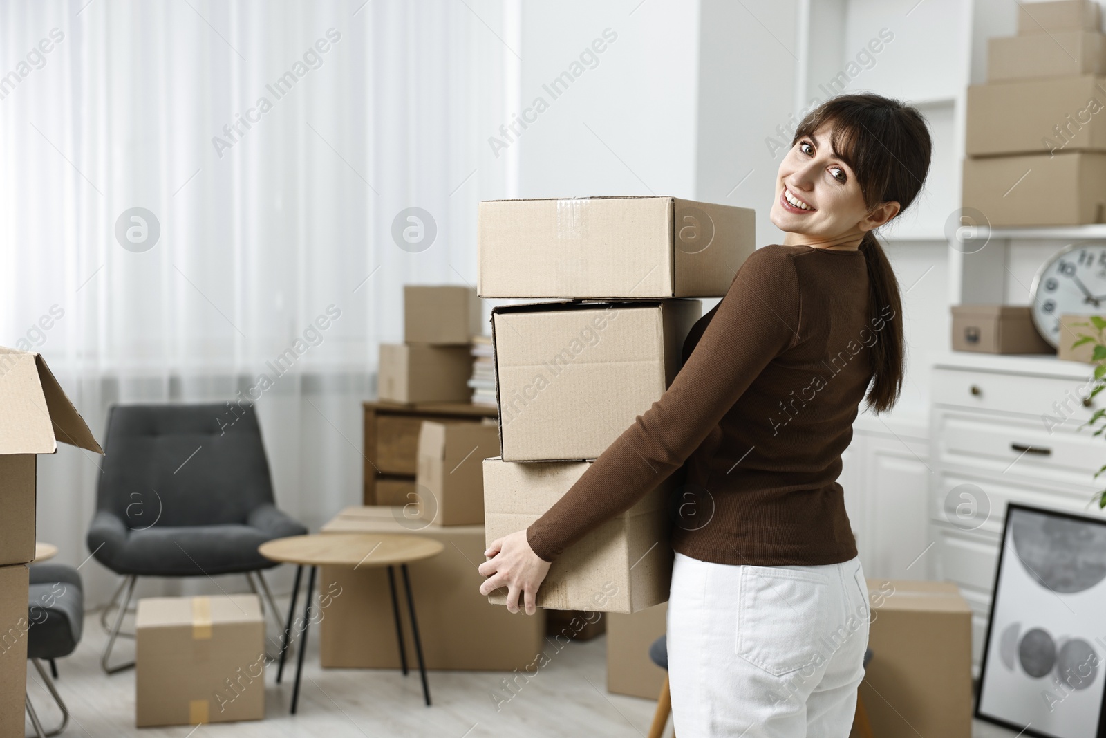 Photo of Moving day. Happy woman with cardboard boxes in her new home