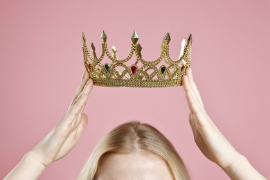 Woman wearing elegant crown on dusty pink background, closeup