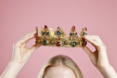 Woman wearing elegant crown on dusty pink background, closeup