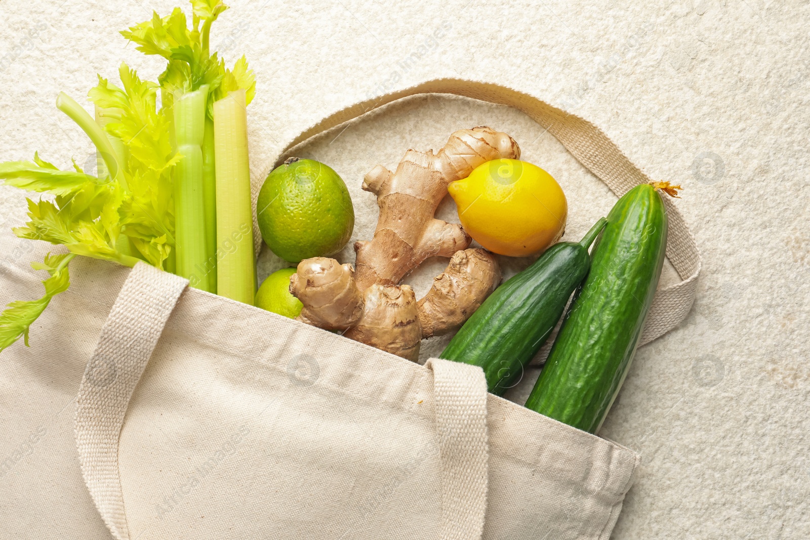 Photo of Eco bag with vegetables, fruits and ginger on white textured table, top view