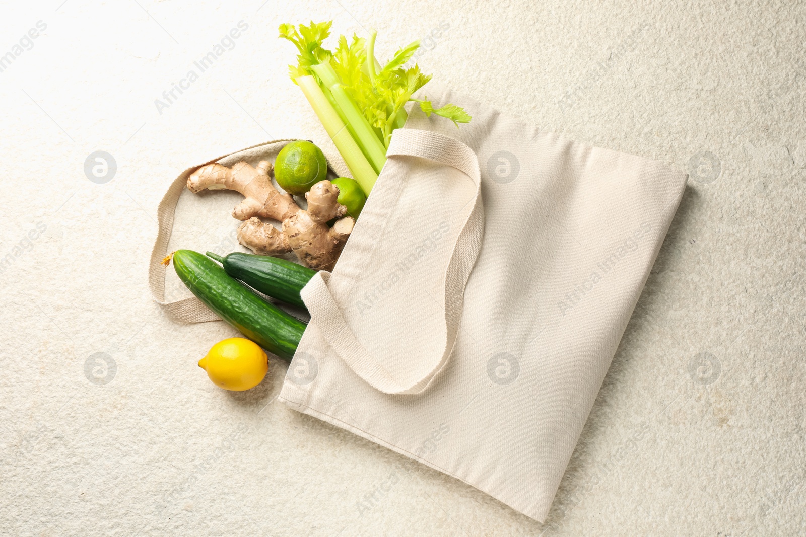 Photo of Eco bag with vegetables, fruits and ginger on white textured table, top view