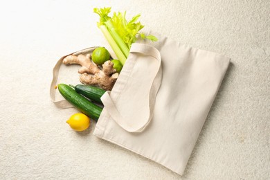 Photo of Eco bag with vegetables, fruits and ginger on white textured table, top view